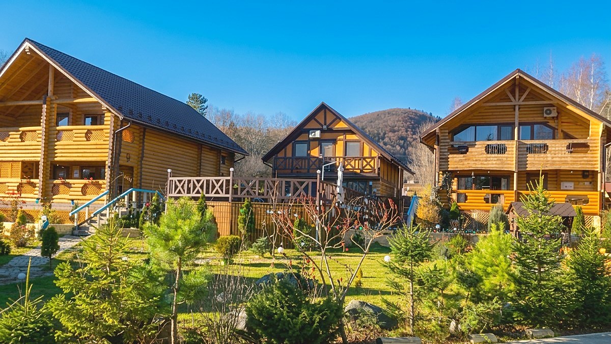Три дерев'яні котеджі Forest Camp на тлі Карпат
